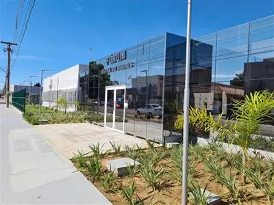 O exterior de um moderno edifício, provavelmente um fórum, com fachada de vidro espelhado. Em destaque na fachada, o nome 